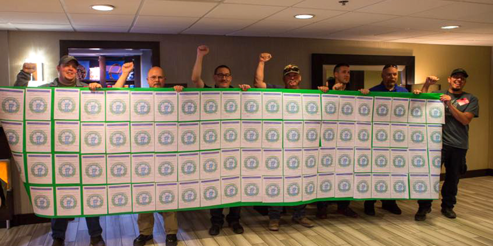 EMS Local 2960 members hold up copies of a petition joined together to form a large banner